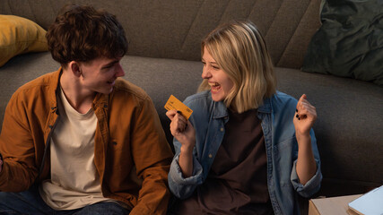 A young man and woman are in the living room discussing a housewarming.