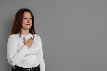 Woman making promise on grey background, space for text. Oath gesture