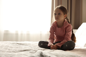 Orphanage concept. Sad girl on bed in room