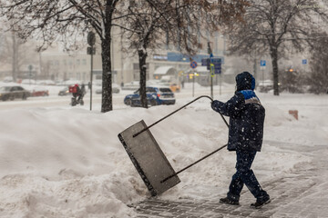 A labouring man shoveling away snow in Moscow, struggling with big banks of snow