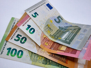 A stack of different euro bills paper banknotes, flat lay close up on a white background. The concept of saving, investment, finance, banking and economy