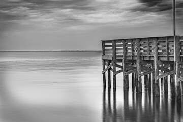 The pier extends over the calm Anclote River Park the ripples of the water provide a timeless feel. Tarpon Springs FL 2024
