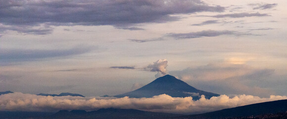 Volcano Emitting Smoke Amidst Cloudy Landscape