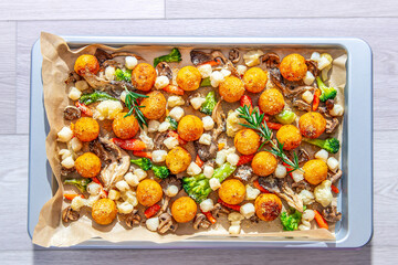 baked potato with scallops, mushrooms and vegetables on a baking sheet