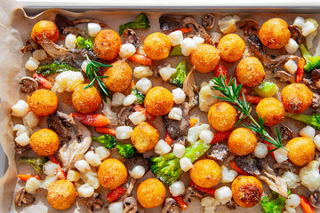 baked potato with scallops, mushrooms and vegetables on a baking sheet