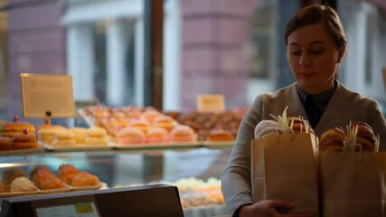 Woman Selects Pastries at a Bakery While Enjoying a Vibrant Atmosphere in the City