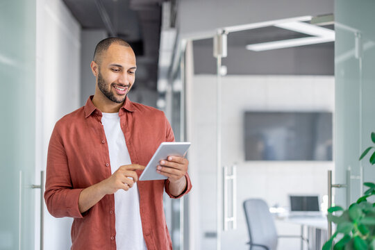 Successful satisfied businessman using tablet computer inside office at workplace, man in casual shirt reading online report, programmer developer testing new software. - Powered by Adobe