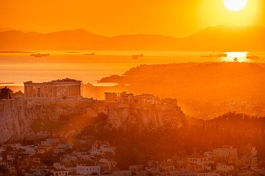 Sunset over Arcopolis hill in Athens. Beautiful orange sky landscape, view from above from Lycabetus Hill, to the Anciend World of Parthenon. Travel to Athens, Greece.
