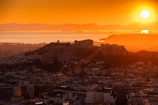 Sunset over Arcopolis hill in Athens. Beautiful orange sky landscape, view from above from Lycabetus Hill, to the Anciend World of Parthenon. Travel to Athens, Greece.