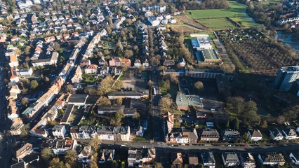 Selbstklebende Fototapeten Aerial view of city blocks with red roofs and green areas. The image shows a sunny day, narrow streets and neat houses surrounded by trees. Ideal for illustrating urbanism or architecture. © EUDPic