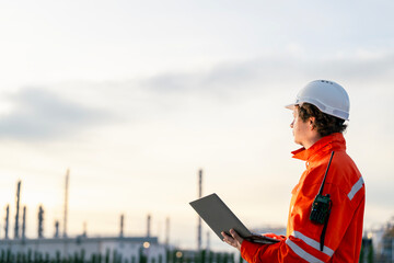 Industrial professional in safety attire analyzing refinery operations using modern technology, showcasing leadership and expertise in industrial safety and infrastructure projects.