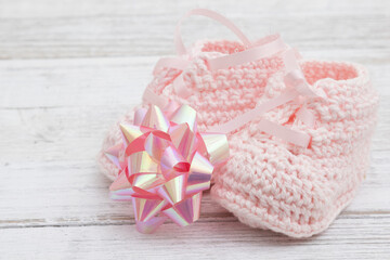 Pink baby booties with a bow on wood