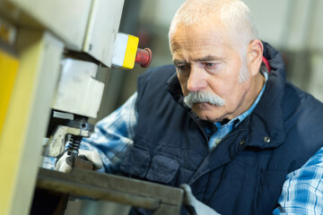 senior worker in factory on the machine