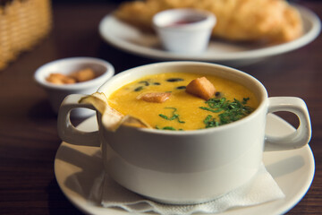 A cup of creamy pumpkin soup with croutons