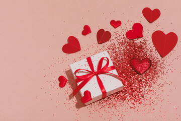 Gift box and red hearts decorated shiny glitter for Valentines Day. Aesthetic conceptual card.