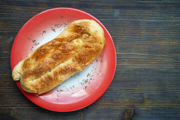 Balkan cuisine. Burek on red plate.  Burek is filled pastry, popular national dish in Balkans. Copy space