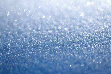 Ice H2O crystals glistening in the winter sun. Macro close up of frozen water crystalline structures, with selective focus on a cold winter morning. Abstract natural background in shades of blue.
