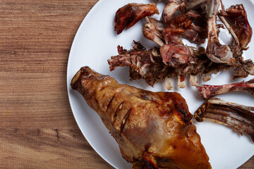 Roast pork head, with remnants of bones and meat, on a white platter, no people, close-up,