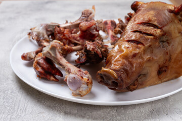 Roast pork head, with remnants of bones and meat, on a white platter, no people, close-up,