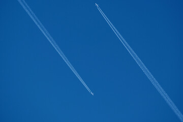 Airplane in the blue sky with contrail. Two planes in the sky.