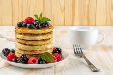 Delicious pancakes with fresh berries on white wooden table. Food concept.
