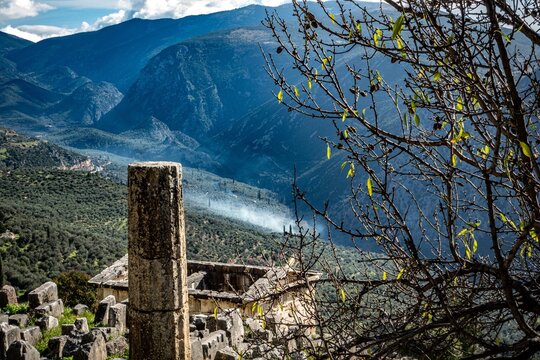 Ancient Delphi. Delfos column on slope with smoke and valley. Greece