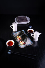 Plato de Temakis con salsa de soya en fondo negro,  sushi de salm&oacute;n. Comida Japonesa.