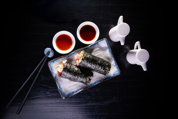 Plato de Temakis con salsa de soya en fondo negro,  sushi de salm&oacute;n. Comida Japonesa. Vista cenital