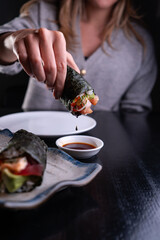 Mujer con cono de temaki de salm&oacute;n y salsa de soya.