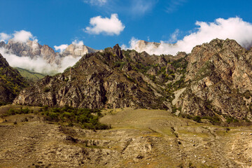 Fototapeta premium Caucasus, mountainous rocky view, blue sky with white cottony clouds