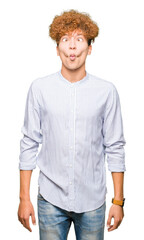 Young handsome business man with afro hair wearing elegant shirt making fish face with lips, crazy and comical gesture. Funny expression.