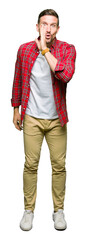Handsome man wearing casual shirt hand on mouth telling secret rumor, whispering malicious talk...