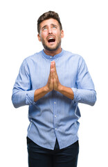 Young handsome man over isolated background begging and praying with hands together with hope...