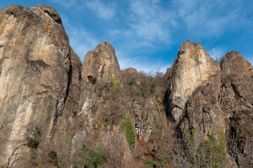 Rocks against blue sky in a canyon covered with mountain forest in winter