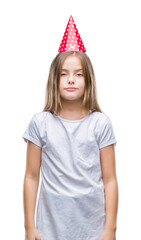 Young beautiful girl wearing birthday cap over isolated background with serious expression on face. Simple and natural looking at the camera.