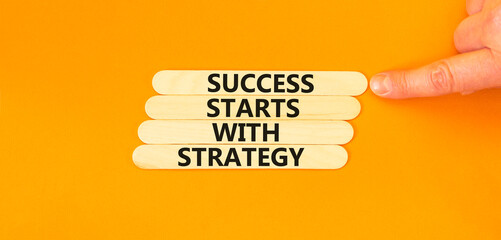 Success starts with strategy symbol. Concept words Success starts with strategy on beautiful wooden sticks. Beautiful orange background. Business and success starts with strategy concept. Copy space.