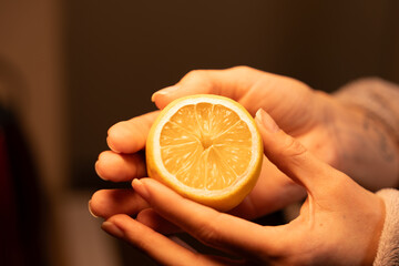 Slicing a fresh lemon held by hands in warm lighting creates a vibrant atmosphere