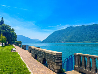 A stunning landscape featuring a calm Iseo lake reflecting the blue sky, Italy. Majestic mountains...