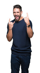 Young handsome man wearing sweater over isolated background shouting with crazy expression doing rock symbol with hands up. Music star. Heavy concept.