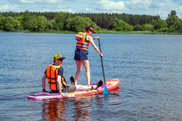 Two young people in life vests paddling on sap board, sport activity