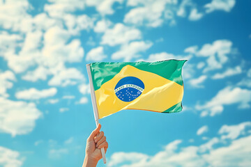 Hand holding Brazil national flag on blue sky. Happy Independence Day, Labor Day, Proclamation of the Republic. Background with copy space for greeting card, banner, poster