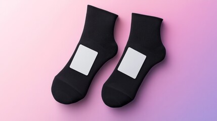 Pair of black ankle socks with blank white labels on pastel background.