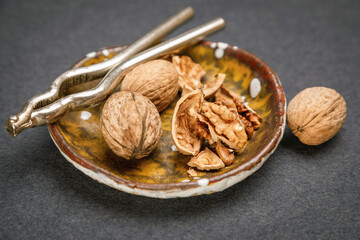Whole and chopped walnuts on a decorative plate and a rustic chive next to them