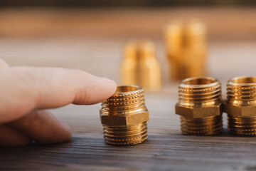 Brass nipple with thread held in the hand. Other hydraulic parts in the background. (selective focus`)