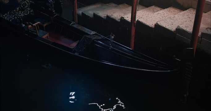 Empty gondola floating on the canals of Venice during the night