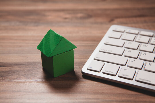 model house and computer keyboard on wooden desk, real estate concept, home insurance and mortgage.