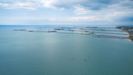 Panoramic view of the water area of the cargo port “Kavkaz”: coastline and berths with dry cargo ships and tankers. Ships waiting for their turn in the distance. Aerial photography.
