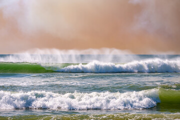 wave breaking on a windy day with a smoke-filled sky