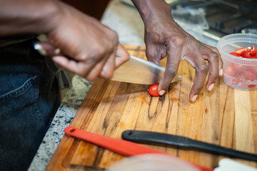 Obraz premium Chef Hands Cutting A Cherry Tomato On A Wooden Cutting Board