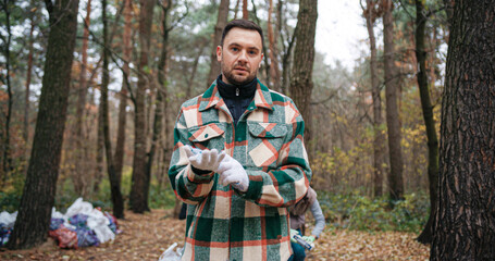 Handsome Caucasian male standing in forest while looking directly at camera. Disappointed after...